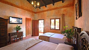 Une chambre d’hôtel avec deux lits, un bureau, une chaise, une télévision et une plante en pot.