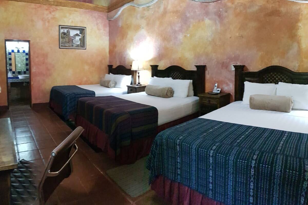 A hotel room with two beds, a wooden table, and a chair.