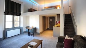 A modern apartment with a dining area, a sofa, a staircase, and a second-floor sleeping area. - Court Residence (Linlithgow)