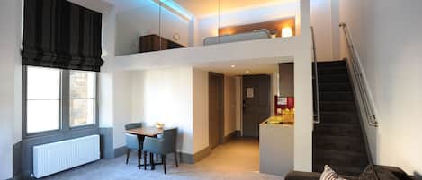 Un appartement moderne comprenant un coin repas, un canapé, un escalier et un espace nuit situé au deuxième étage.