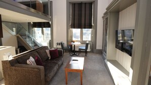 A modern living room with a sofa, a small table, a TV, and a staircase. - Court Residence (Linlithgow)