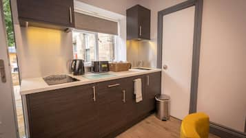 Suite (Courtyard Apartment Suites) | Private kitchen | Full-sized fridge, microwave, coffee/tea maker, cookware/dishes/utensils