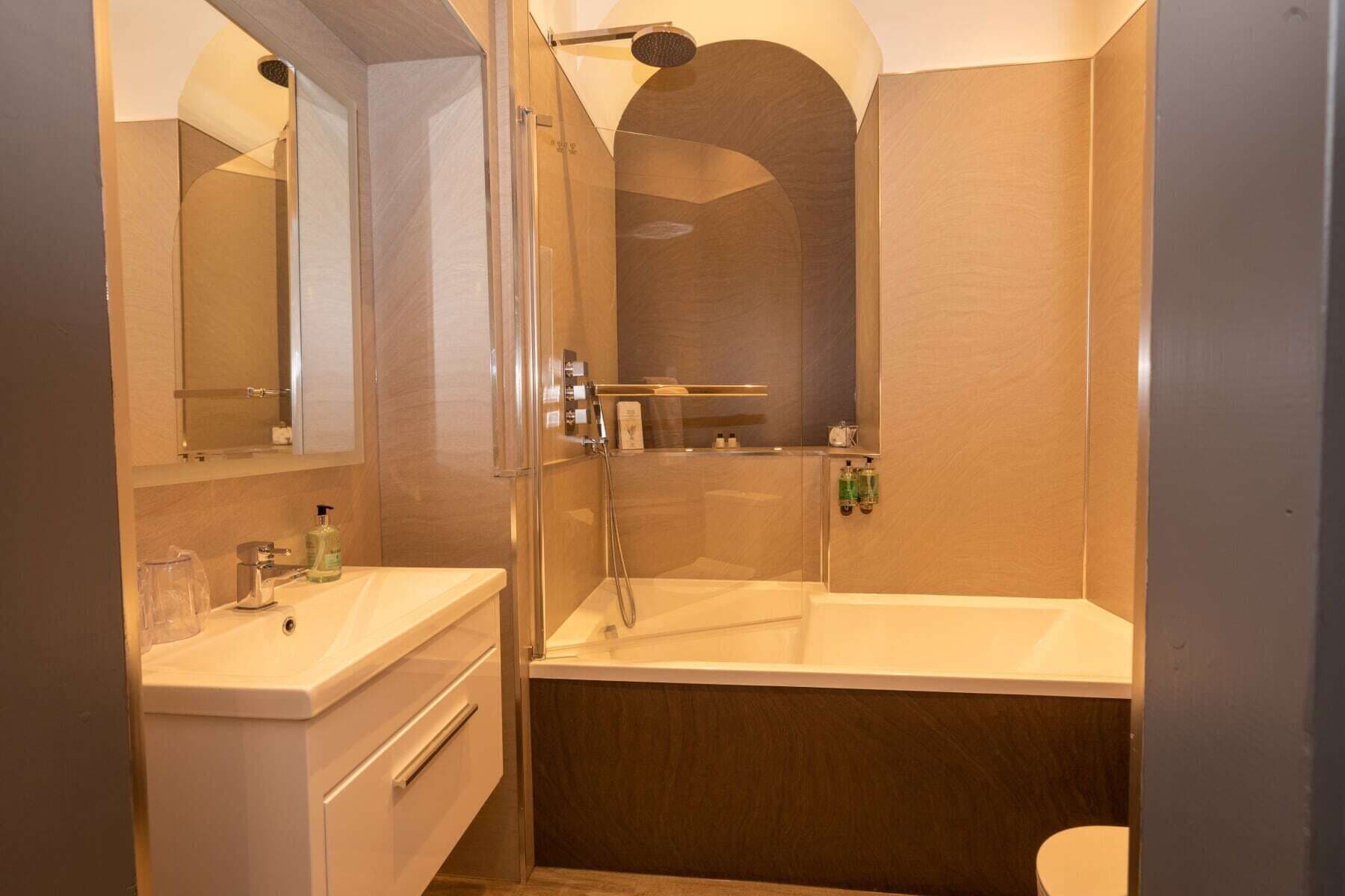 A modern bathroom with a glass-enclosed shower, a standalone bathtub, and a vanity with a mirror.