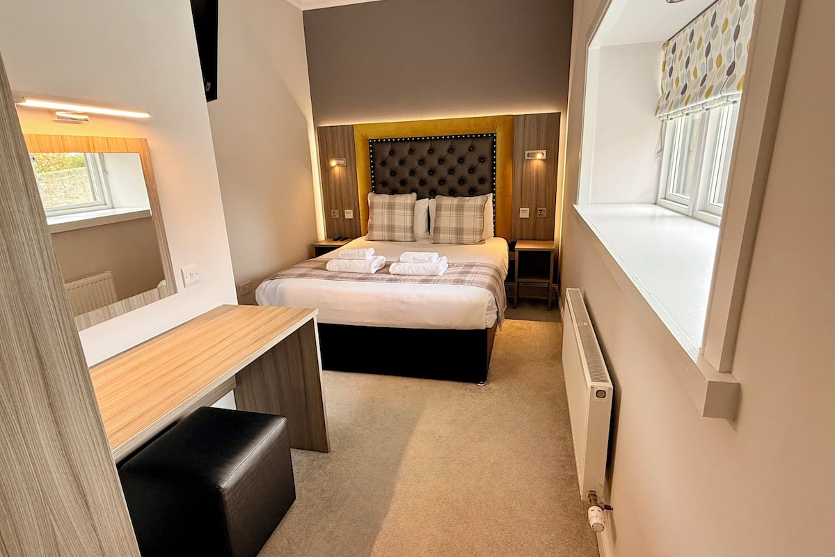 Une chambre d’hôtel de taille réduite, comprenant un lit, un petit bureau et une fenêtre.
