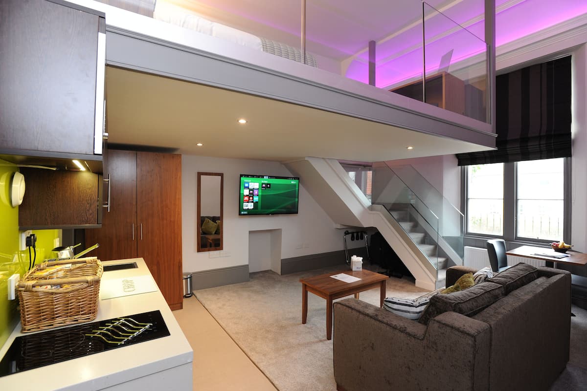Un espace de vie moderne comprenant une cuisine, un coin repas et un escalier menant à un niveau supérieur.
