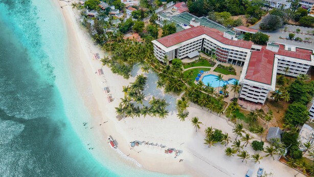 An aerial view of a beachfront hotel with a swimming pool, beach umbrellas, and palm trees. - Mombasa Continental Resort (Mombasa)