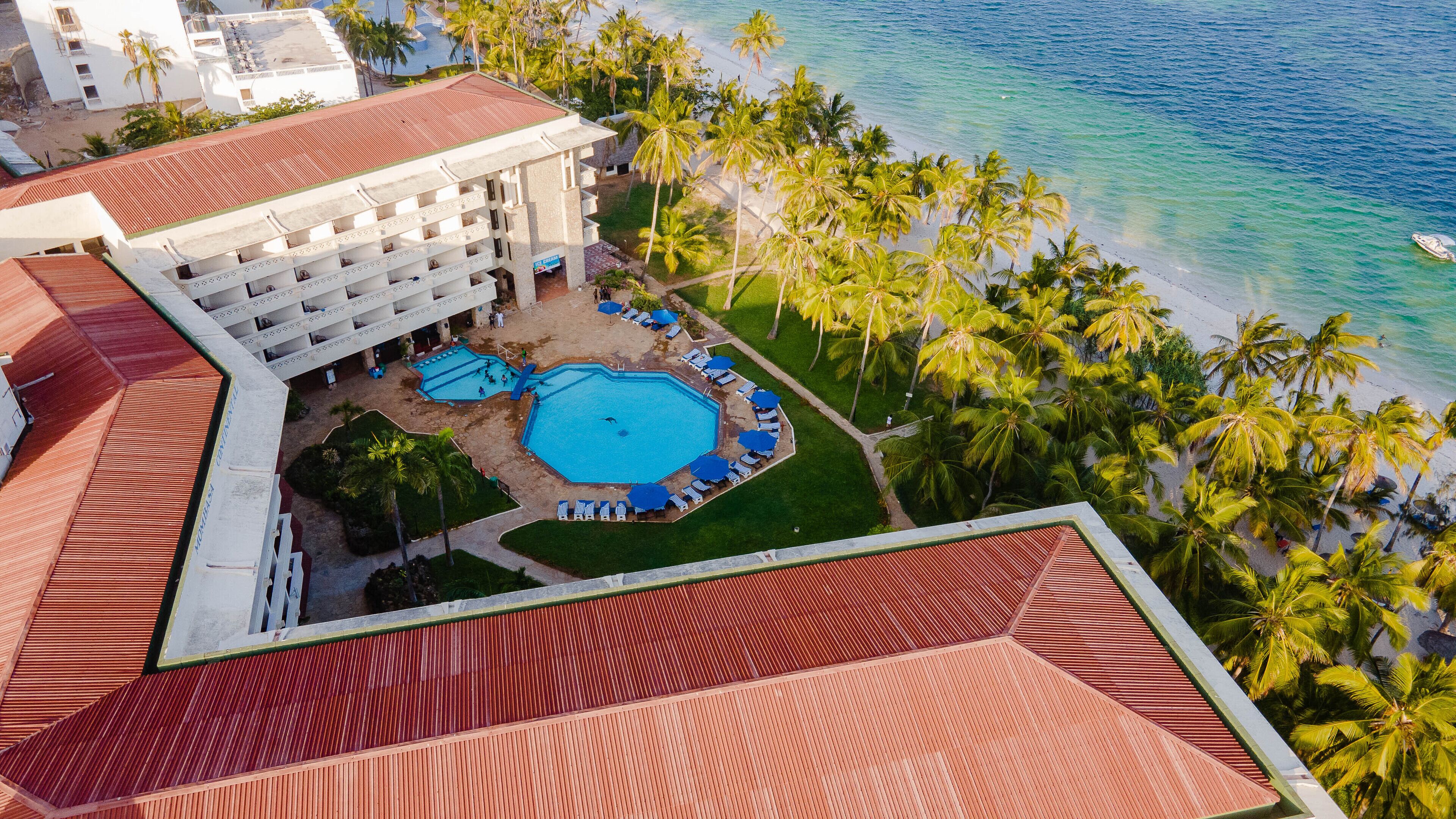 A resort with a large pool, palm trees, and a beach.