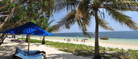 Aan het strand, wit zand, ligstoelen aan het strand, parasols