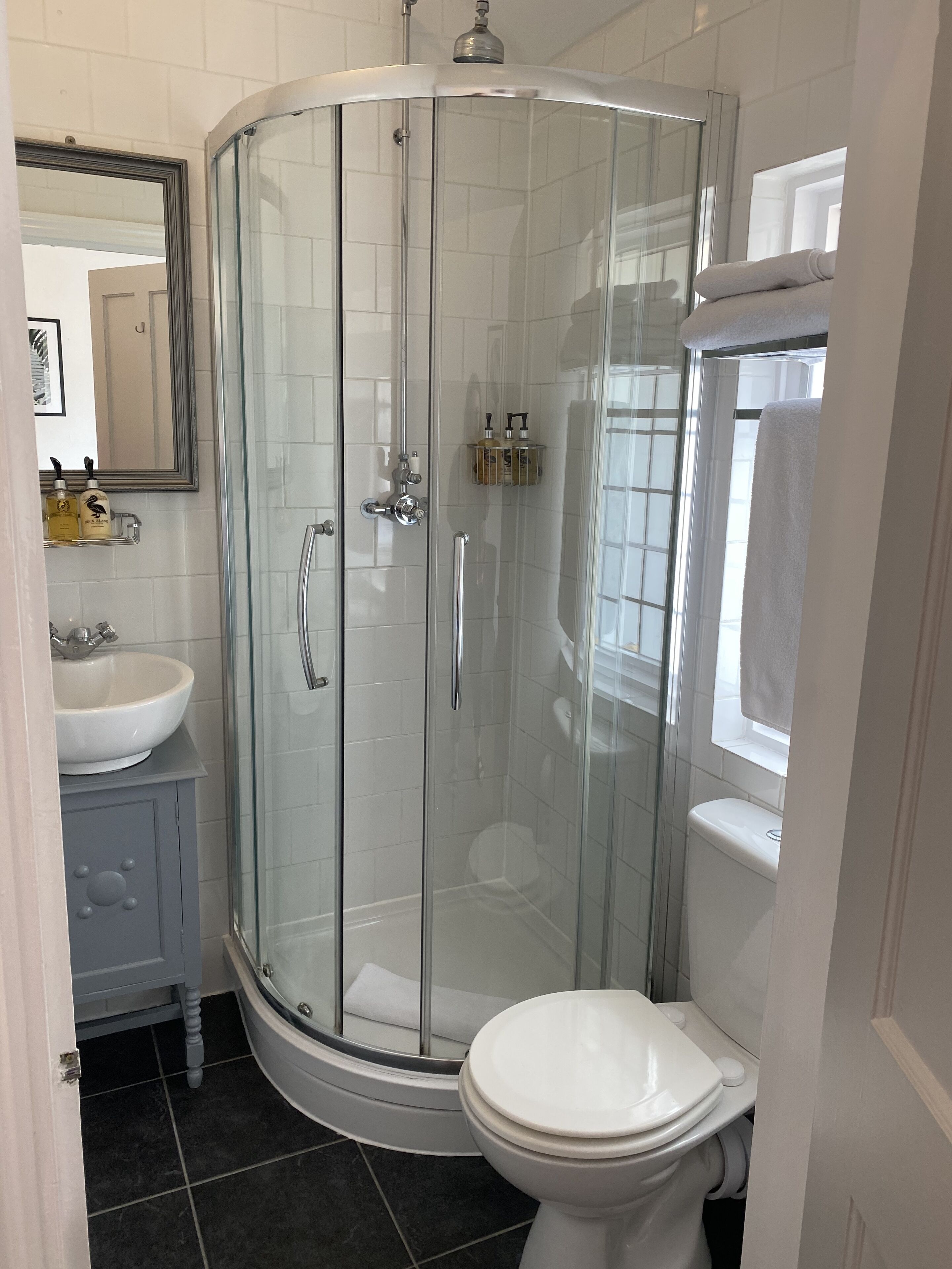 A modern bathroom with a glass-enclosed shower, a white toilet, and a vanity with a sink.