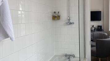 Uma casa de banho moderna com banheira, chuveiro e área de duche separada por vidro.