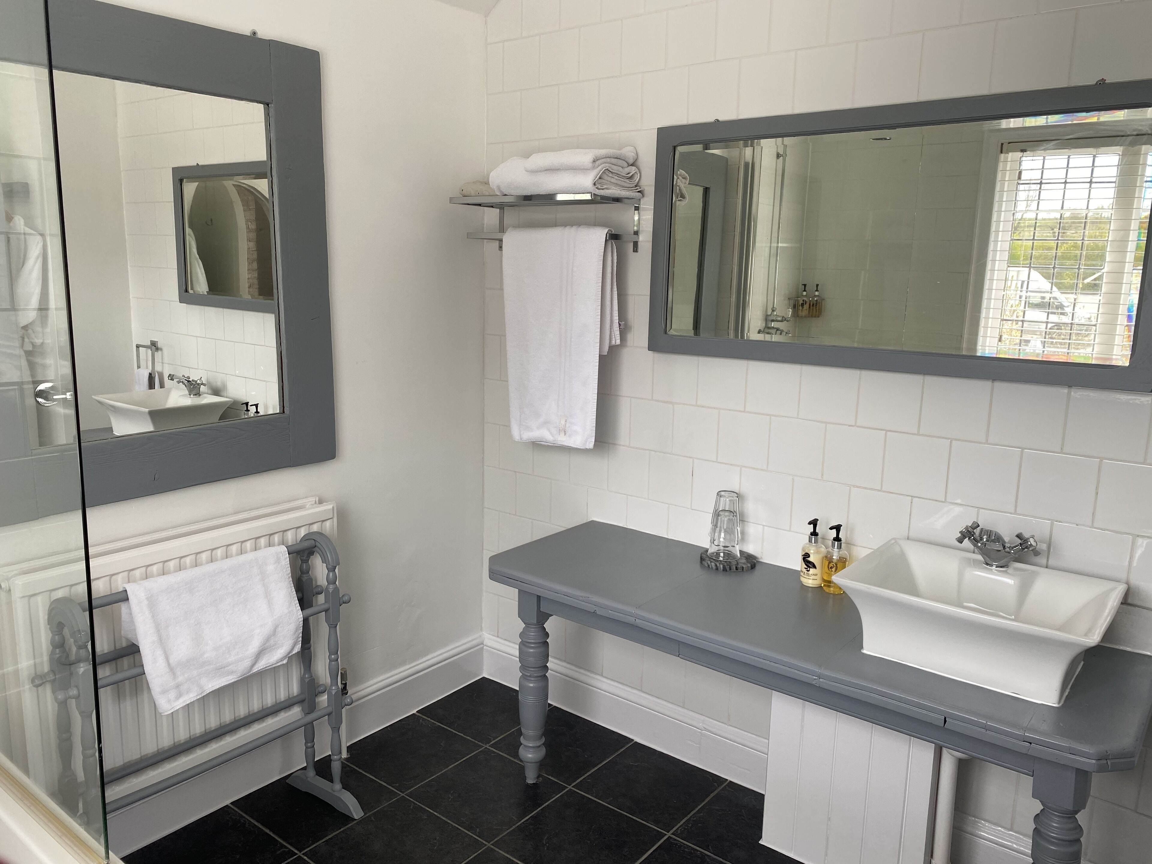 A bathroom with a white sink, a mirror, a towel rack, and a glass shower enclosure.