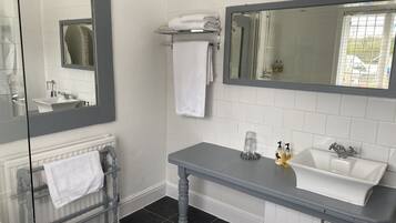 A bathroom with a white sink, a mirror, a towel rack, and a glass shower enclosure.