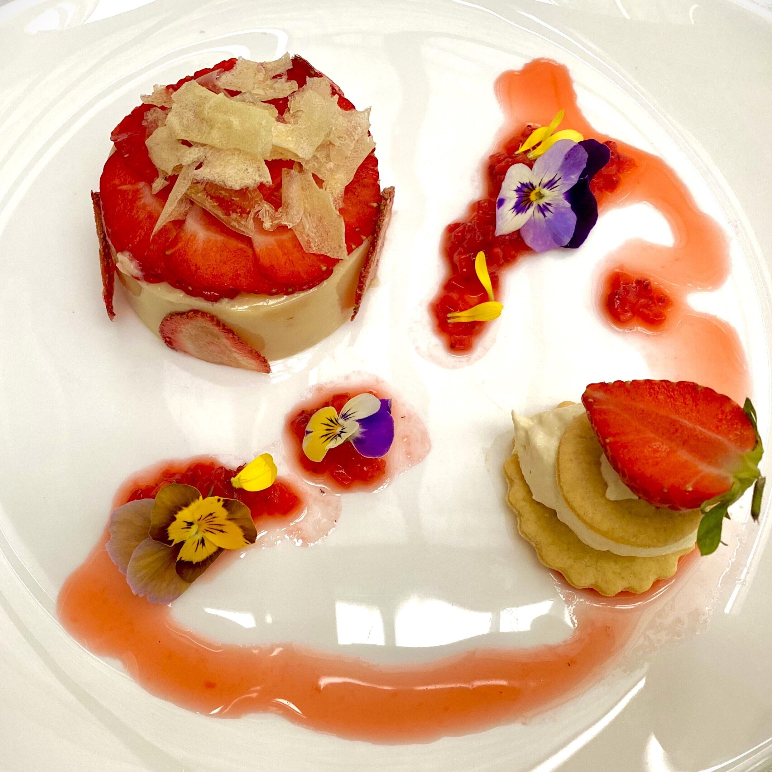 Un plato de postre con diversas composiciones de fruta y decoración floral.