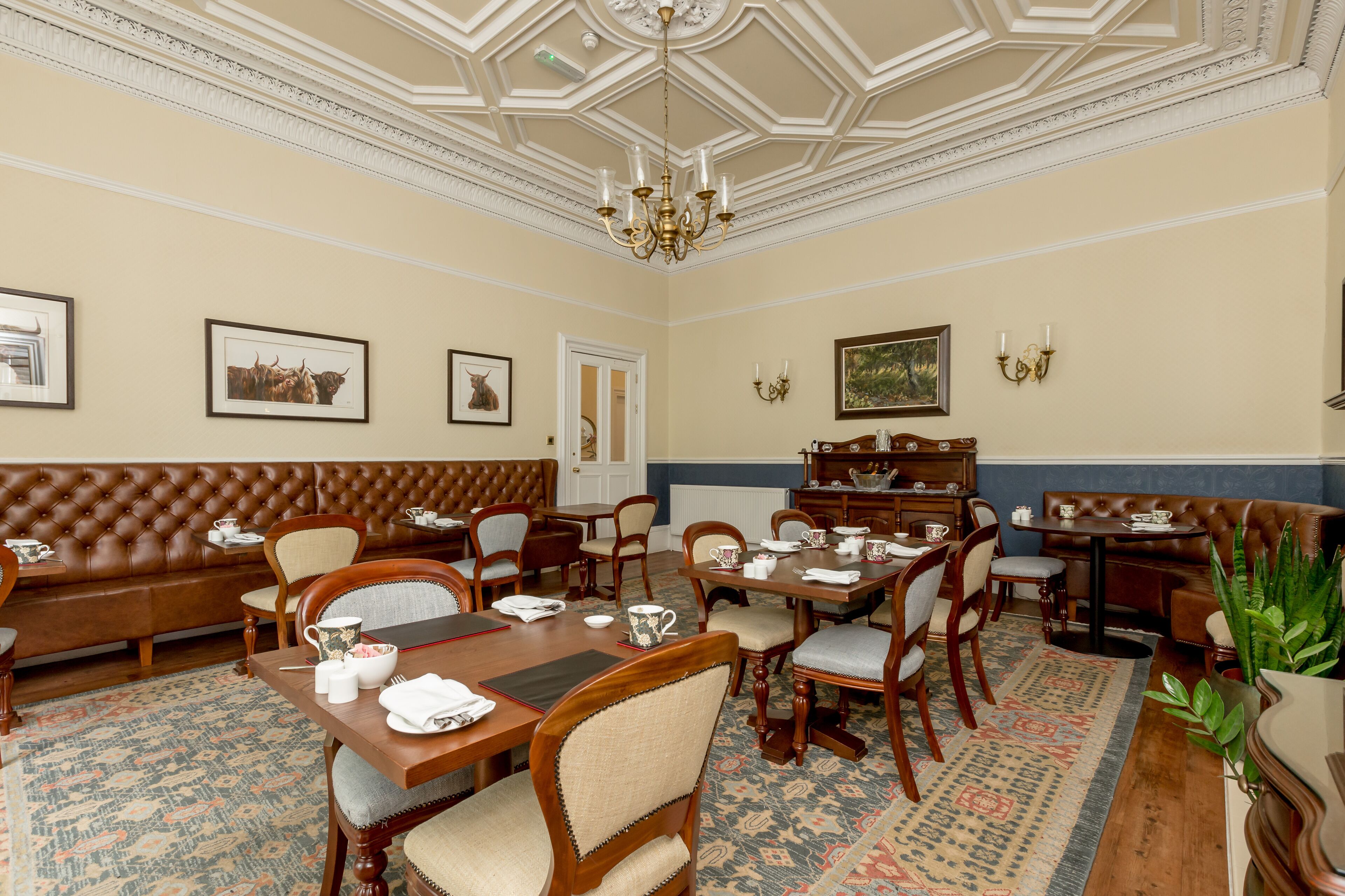 Une salle à manger élégante, dotée d’un haut plafond, de lustres et d’un tapis à motifs.