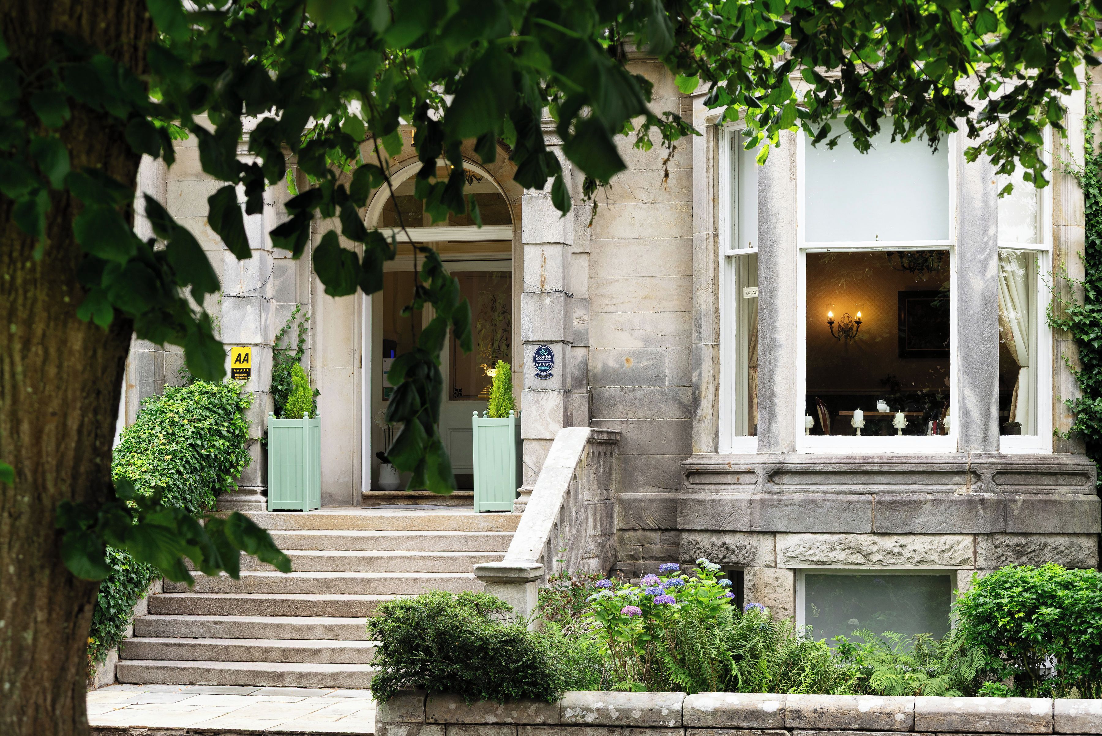 A stone building with a set of steps leading to a door, a sign indicating a 4-star rating, and a window with a light fixture.