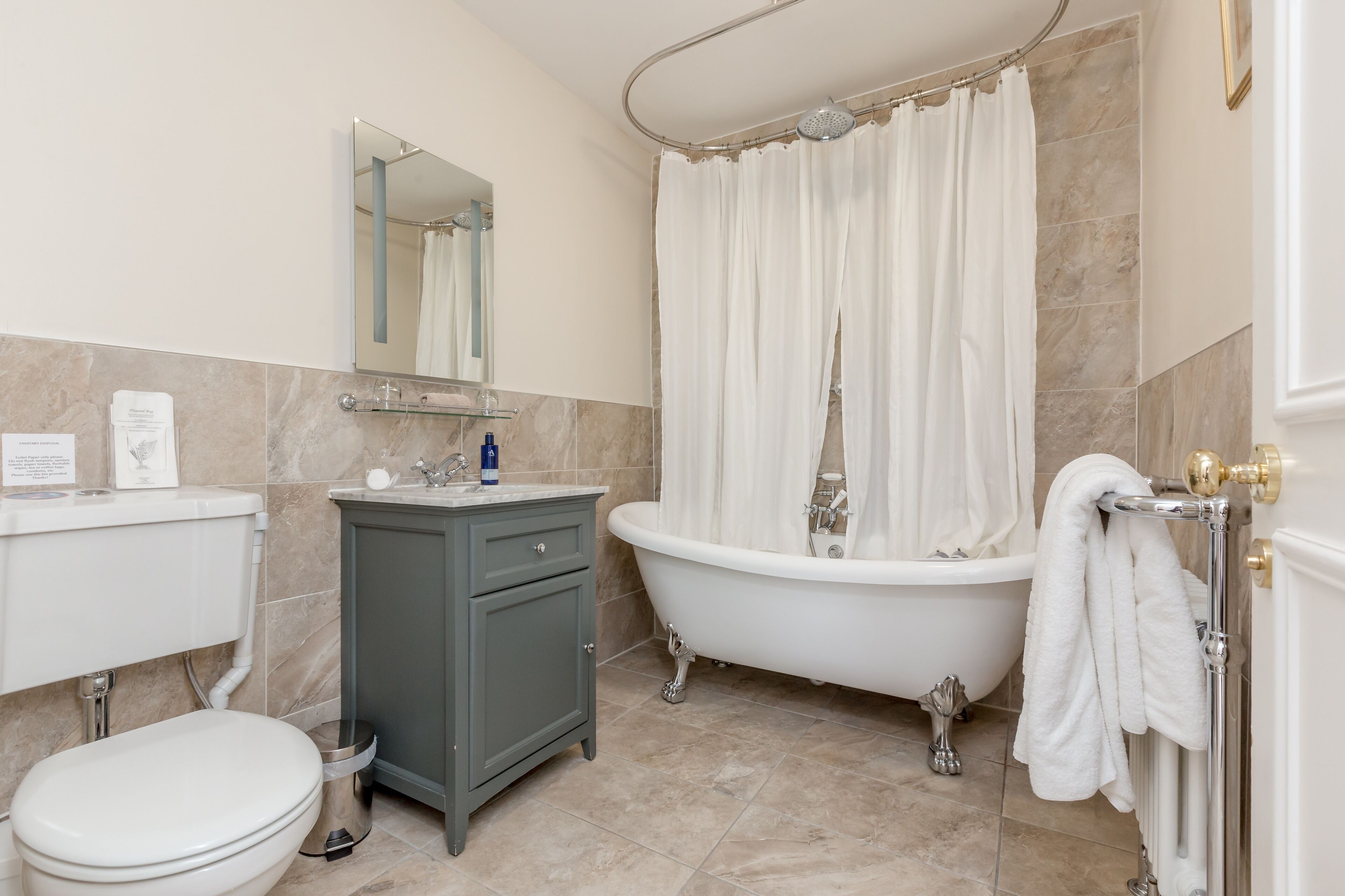 Une salle de bain comprenant des toilettes, un meuble-lavabo, une baignoire et un rideau de douche.