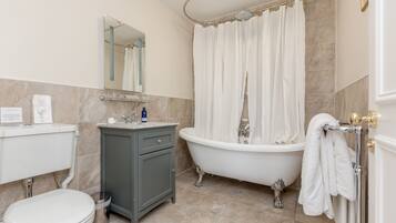 Une salle de bain comprenant des toilettes, un meuble-lavabo, une baignoire et un rideau de douche.