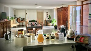 A dining area with a long table, chairs, and a coffee machine. There are various containers and jars on the counter. - Domaine Joseph LAFARGE Wine Resort Oeno-tonneaux expérience (Lugny)