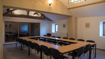 A conference room with a long table and chairs, stone walls, and a sloped ceiling with exposed beams.