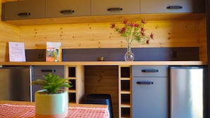 A compact kitchen with wooden cabinets, a stainless steel refrigerator, and a small potted plant on the table. - Domaine Joseph LAFARGE Wine Resort Oeno-tonneaux expérience (Lugny)