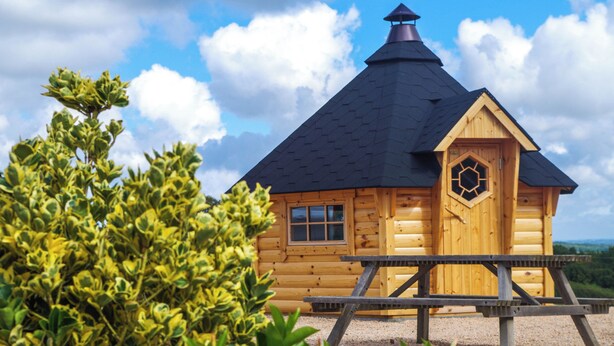 A wooden cabin with a hexagonal window, a chimney, and a picnic table in front. - Domaine Joseph LAFARGE Wine Resort Oeno-tonneaux expérience (Lugny)