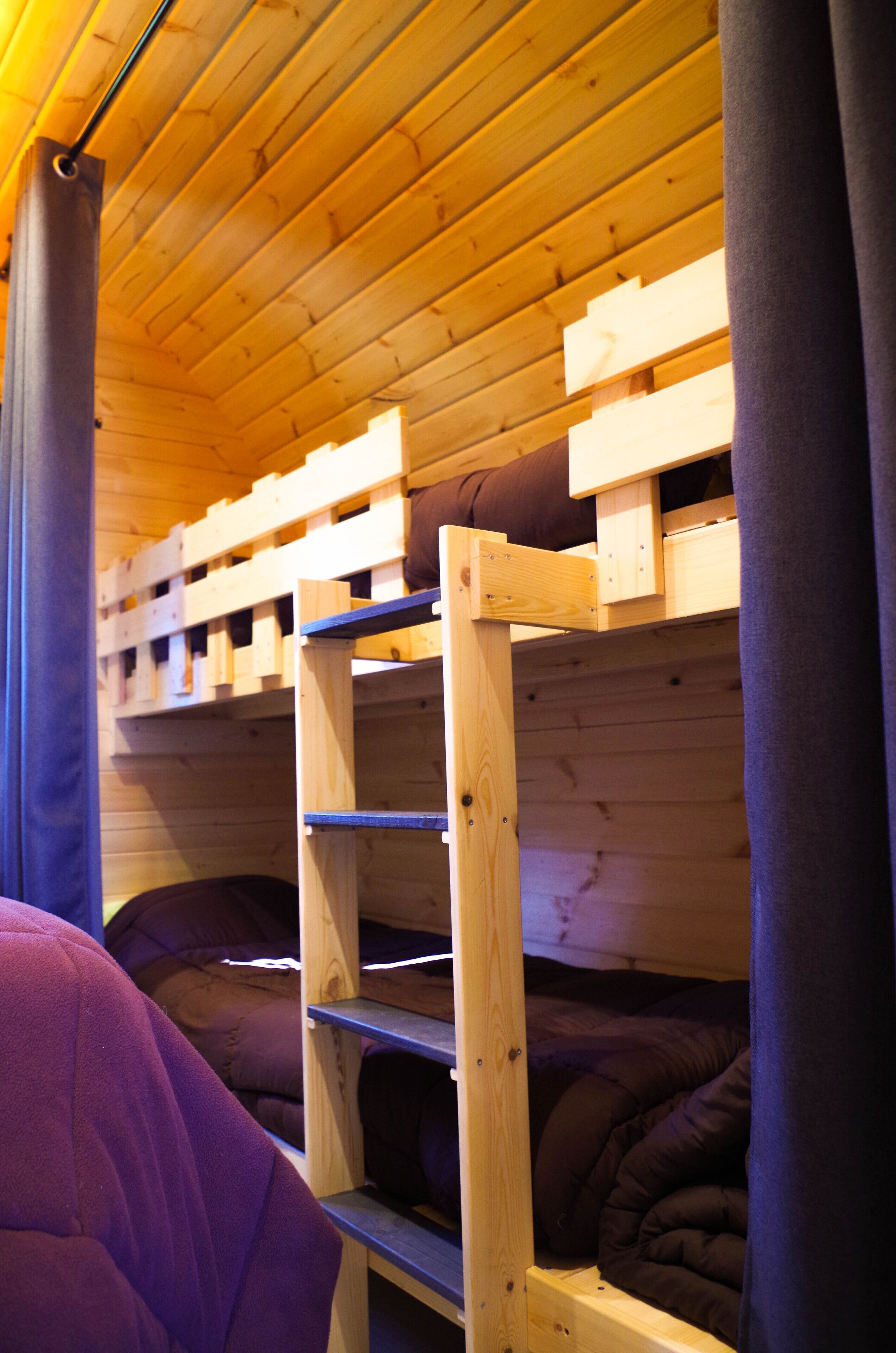 Ein Holzbett mit Etagen, einer wengefarbenen Decke und einem hölzernen Kopfteil.