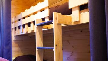 Ein Holzbett mit Etagen, einer wengefarbenen Decke und einem hölzernen Kopfteil.