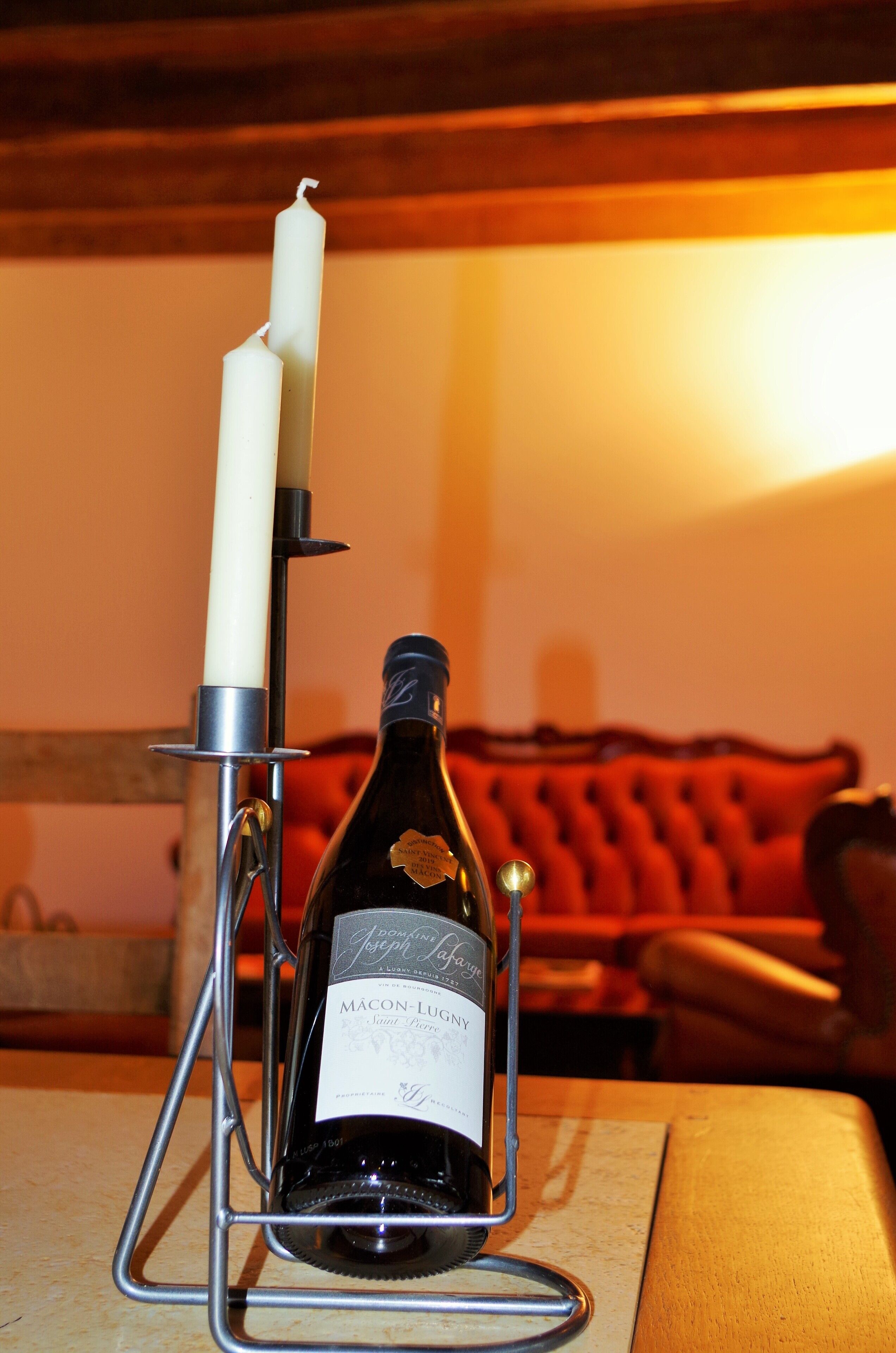 A bottle of Macon-Lugg wine on a metal stand with a candle beside it.