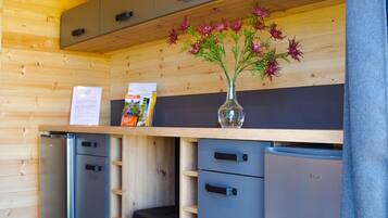 A compact kitchen with wooden cabinets, a black stool, and a refrigerator.