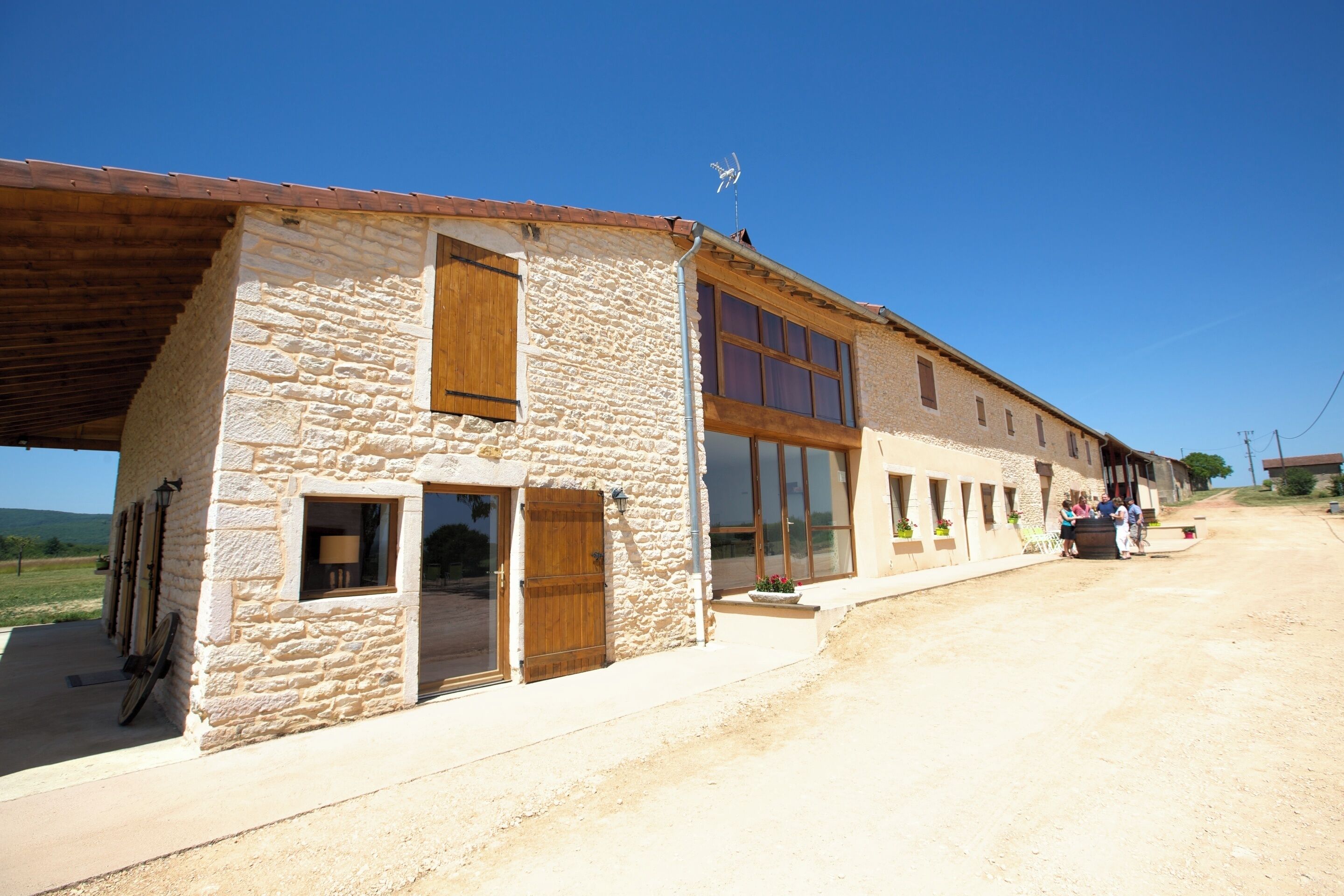 Un edificio de piedra con un amplio acceso abierto, una puerta de madera y una ventana.