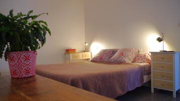 Een slaapkamer met een bed, nachtkastjes, een lamp en een potplant.