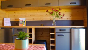 Une cuisine de taille réduite, avec des meubles en bois, un réfrigérateur en acier inoxydable et une petite plante en pot posée sur la table.