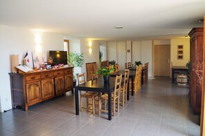 Un vaste espace dédié à la salle à manger, avec une longue table et de nombreuses chaises, des meubles en bois et un téléviseur.