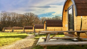Une rangée de cabanes en bois, dotées d’entrées en arc de cercle, chacune ayant une table de pique-nique devant.