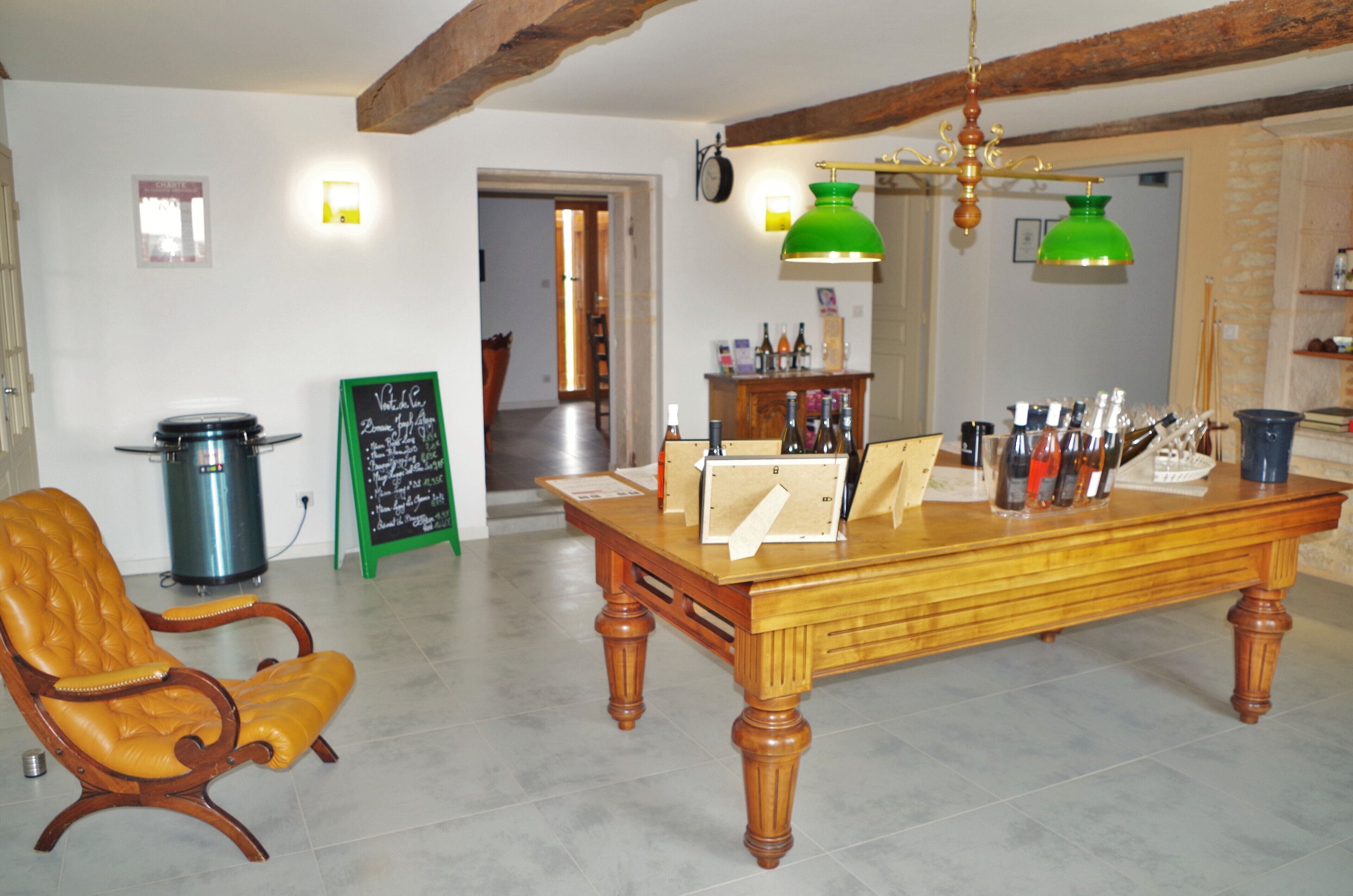 Een eetruimte met een houten tafel, een lederen stoel en een groene hanglamp.