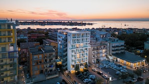 A multi-story hotel with balconies, a parking lot, and a view of the waterfront. - Smart Hotel Mediterraneo (Chioggia)