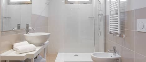 Un baño moderno con un lavamanos grande, un bidé, un inodoro y una zona de ducha.