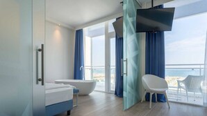 A modern bathroom with a bathtub, a shower, and a large window offering a view of the sea. - Smart Hotel Mediterraneo (Chioggia)
