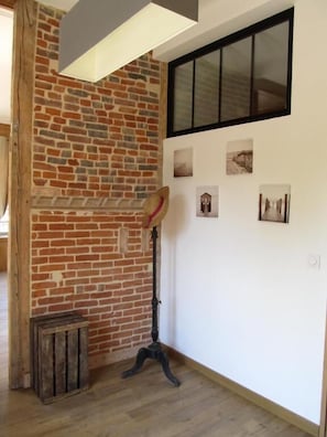 A room with exposed brick walls, a wooden floor, a black floor lamp, and a window with blinds.