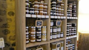 A wooden shelf with multiple jars of preserves, each labeled with their name and price. - A l'Ecole Buissonnière (Honfleur)