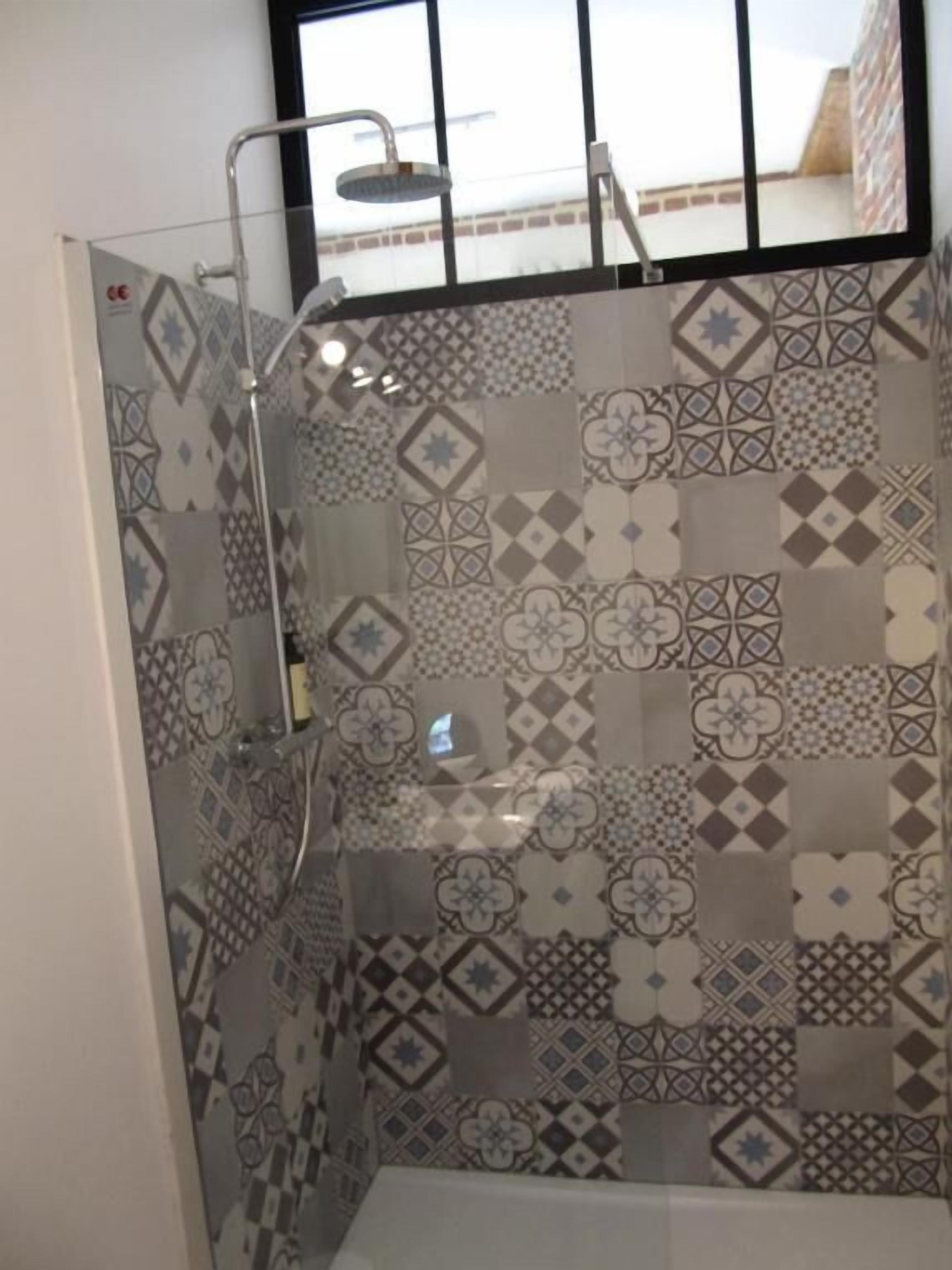 A shower with a glass door and a view of a building outside.