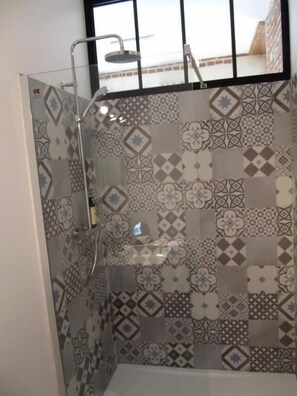 A shower with a glass door and a view of a building outside. - A l'Ecole Buissonnière (Honfleur)