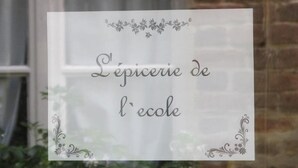 A sign with decorative floral designs and text in French. - A l'Ecole Buissonnière (Honfleur)
