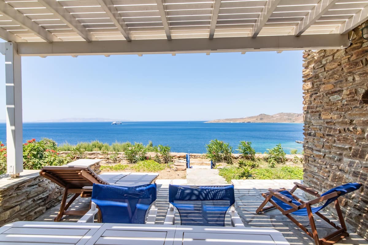 A covered outdoor seating area with a view of the sea.