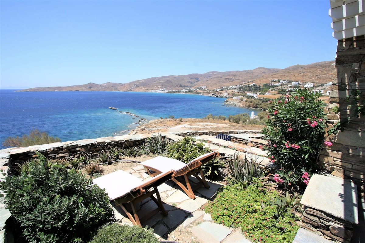 A coastal view with a stone bench and potted plants.