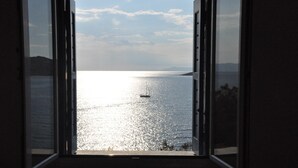An open door leading to a room with a view of a calm sea and a boat. - Stavros Bay (Tinos)