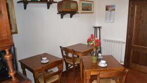 A dining area with two wooden tables and four chairs, a vase with red flowers, and a calendar on the wall. - La Rosa di Firenze (Florence)
