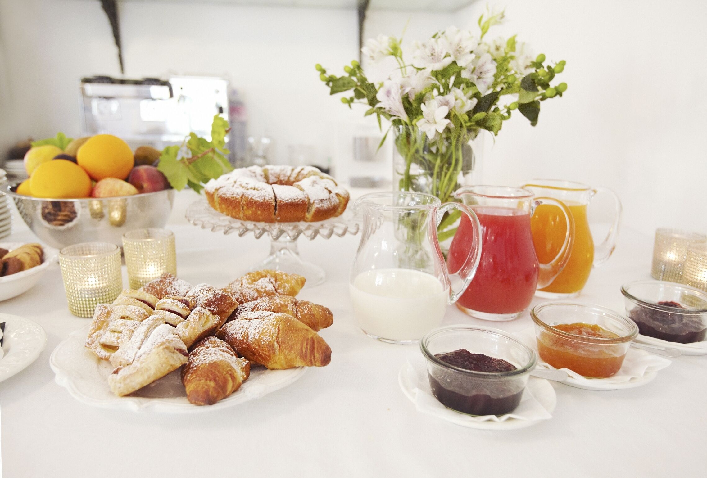 Een ontbijttafel met gebak, fruit en drankjes.