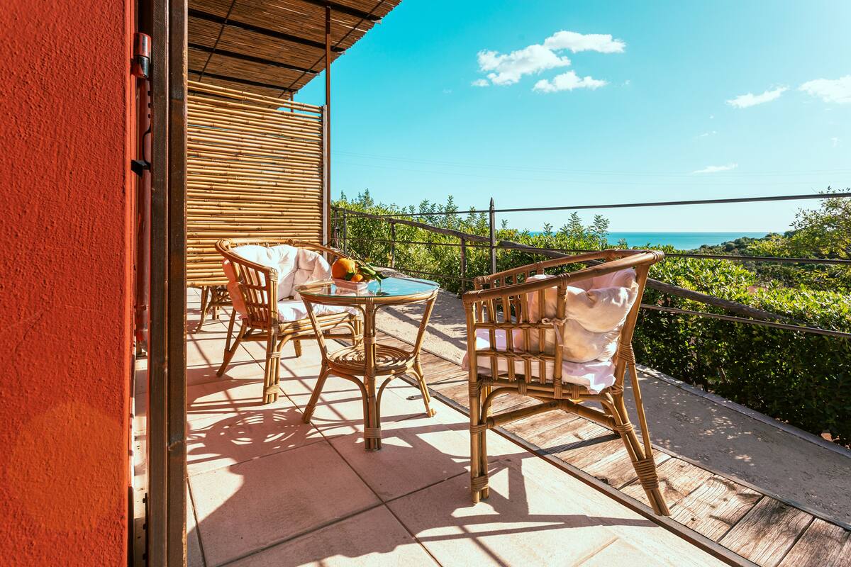 An outdoor patio with wicker furniture and a view of the ocean.
