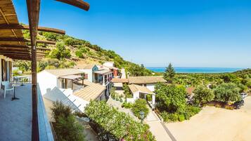 Un villaggio costiero con case dai tetti in terracotta, un percorso pedonale e vista sul mare.